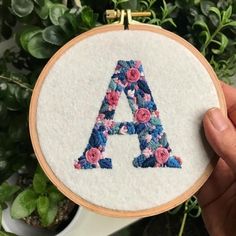 someone is holding up a cross stitched letter