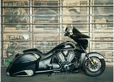 a black motorcycle parked in front of a wall with graffiti on it's side