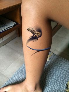 a lizard tattoo on the leg of a woman