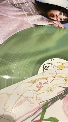 a woman laying on top of a bed next to a green record