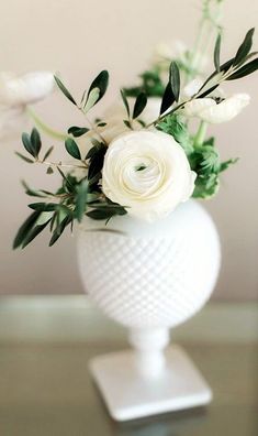 a white vase filled with flowers on top of a table