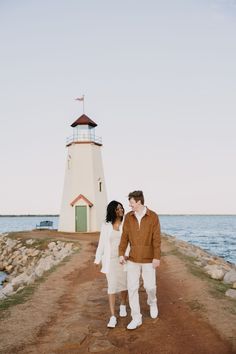 a man and woman standing in front of a light house