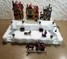 a small town with houses and horses on top of snow drifting in front of a white wall