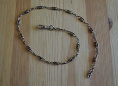 This beautiful watch chain is made of sterling silver with gold fill highlights on the links. Condition overall is good with some general age wear and tarnish, one link has a small notch where it was probably tested for gold, one end has a hinged clip for the watch and the other end has a solid ring where a fob could be clipped on. There are illegible hallmarks on the end near the clip. A couple links are slightly curved from age/use, they could be straightened with pliers. This is long enough t Antique Style Oval Link Chain Necklace, Vintage Silver Chain Link Necklace, Vintage Wheat Chain Necklace For Formal Occasions, Antique Figaro Chain Link Necklace, Antique Figaro Link Chain Necklace, Antique Figaro Chain Necklace, Antique Engraved Link Necklaces, Antique Link Necklaces With Engraving, Antique Engraved Link Necklace