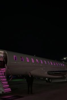 a large jetliner sitting on top of an airport tarmac at night with stairs leading up to it