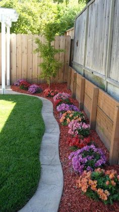 a flower bed in the middle of a yard with flowers growing on it's sides