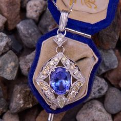 This pleasing 18k white gold pendant is centered with an oval cut tanzanite that weighs 3.57 carats, and is set in a four-prong setting. The tanzanite is surrounded by eighteen (18) bead set round brilliant cut diamonds, and one (1) bezel set pear brilliant cut diamond accent. The pendant is topped by a bead set round brilliant cut diamond and a 14k white gold bail. The pendant measures 41.5mm long, including the bail, by 20.7mm wide. It hangs on an 18-inch long, 1.0mm wide, 14k white gold cable Formal Tanzanite Multi-stone Gemstones, Luxury Oval Tanzanite Necklaces, Luxury Tanzanite Pear-shaped Jewelry, Oval Tanzanite Necklace Fine Jewelry, Luxury Oval Tanzanite Jewelry, Luxury Pear-shaped Tanzanite Jewelry, Fine Jewelry Tanzanite Necklace, Brilliant Cut Tanzanite Gemstones For Gift, Brilliant Cut Tanzanite Gemstones As Gift