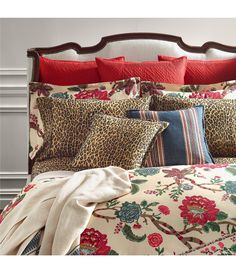 a leopard print comforter and pillows on a bed with red trim around the headboard