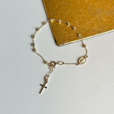 14KT yellow gold chain bracelet with beads, cross charm + Miraculous Medal with diamond-cut detailing. Makes a great gift for 1st communion, holidays, or birthday! Length: 6" with .75" extender Cable chain width: 1mm 14k spring ring clasp Charm length: 13.1mm Charm width: 6.4mm Weight: 2.38 grams Made in Italy Adjustable Yellow Gold Crucifix Jewelry, Adjustable Gold Rosary Bracelet With Charms, Gold Hypoallergenic Cross Bracelet, Adjustable Gold Rosary Bracelet With Miraculous Medal, Gold Bracelets With Round Beads For First Communion, Rosary Bracelet With Cross And Adjustable Chain For Gifts, Adjustable Chain Cross Rosary Bracelet As Gift, Adjustable Cross Rosary Bracelet As Gift, Adjustable Gold Rosary For First Communion