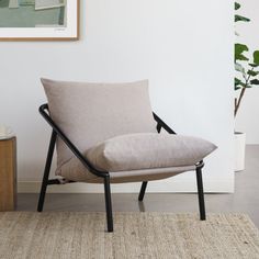 a chair sitting on top of a rug next to a potted plant