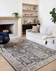 a living room with a couch, chair and rug on the floor in front of a fireplace