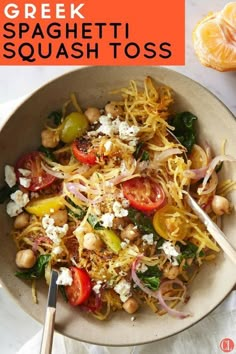 a bowl filled with spaghetti and vegetables on top of a white table next to an orange slice