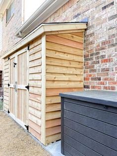 a wooden storage shed next to a brick building