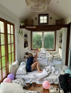 a woman sitting on top of a bed in a room filled with pillows and balloons