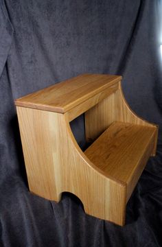 a wooden step stool sitting on top of a black cloth