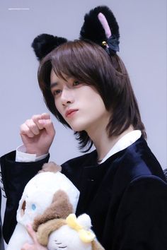 a young man holding a stuffed animal in his right hand and wearing bunny ears on top of his head