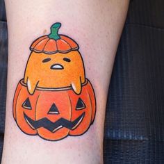 an orange pumpkin with a face drawn on it's side, sitting next to a persons leg