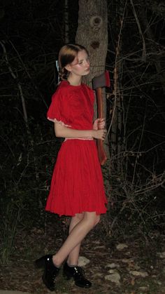 a woman in a red dress holding an ax