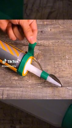 a person is using a green and white pen to cut something out of the side of a piece of wood