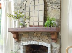 a living room with a stone fireplace and potted plants on top of the mantle