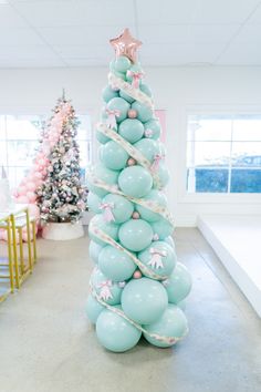 a christmas tree made out of balloons in the middle of a room with other decorations