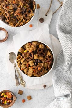 two bowls filled with cereal and pretzels on top of a white tablecloth