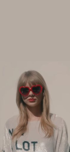 a woman wearing red heart shaped sunglasses standing in front of a white wall with the words love written on it