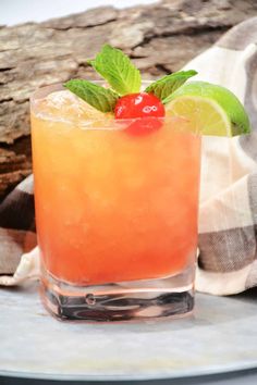 a close up of a drink in a glass with a cherry on the rim and green leaves