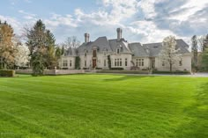 a large white house sitting in the middle of a lush green field with lots of trees