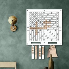 a crossword puzzle is hanging on the wall next to a wooden chair and vase