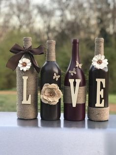 three wine bottles decorated with burlocks and flowers