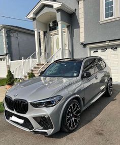 a silver bmw suv parked in front of a house