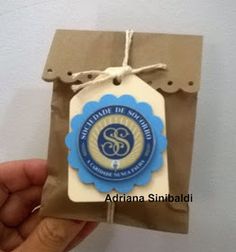 a hand holding a brown paper bag with a blue and white label on it that says,