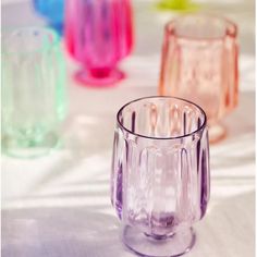 several different colored glass cups sitting on a table