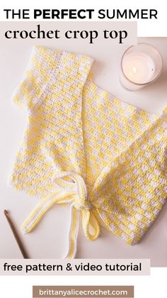 a yellow and white knitted blanket next to a candle