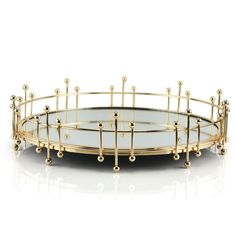 a round glass tray with gold beads on the bottom and sides, sitting on a white surface