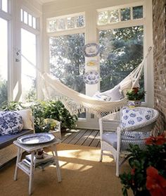 a porch with hammock, chairs and potted plants on the side wall