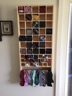 a wooden shelf filled with ties next to a wall mounted tie rack on the side of a wall