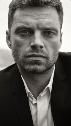 a black and white photo of a man in a suit looking at the camera with a serious look on his face