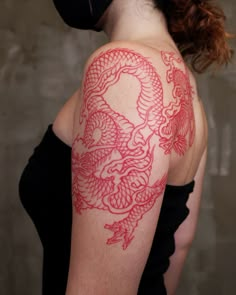 a woman with a red dragon tattoo on her arm and shoulder is wearing a black mask