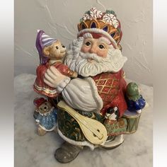 a figurine of santa claus holding a baby bear and other toys on a table