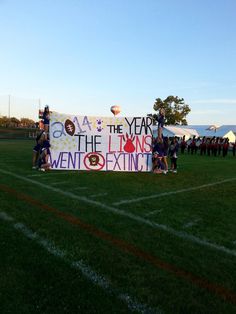 some people are holding up a large banner on the field with balloons in the sky