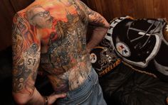 a man with tattoos on his back standing next to a baseball glove