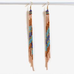 two pairs of beaded earrings hanging from a hook on a clothes line in front of a white background