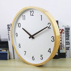 a clock sitting on top of a wooden table next to books and a bookcase