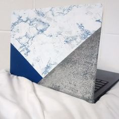 a laptop computer sitting on top of a white bed next to a pillow and blanket