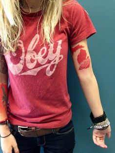 a woman with tattoos on her arms and arm is standing in front of a blue wall