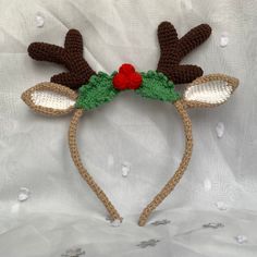 a crocheted reindeer headband with red nose and green antlers on it