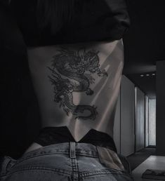 the back of a woman's body with a dragon tattoo on her lower back