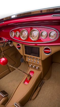 the interior of a classic car with red trim and gauges on it's dashboard